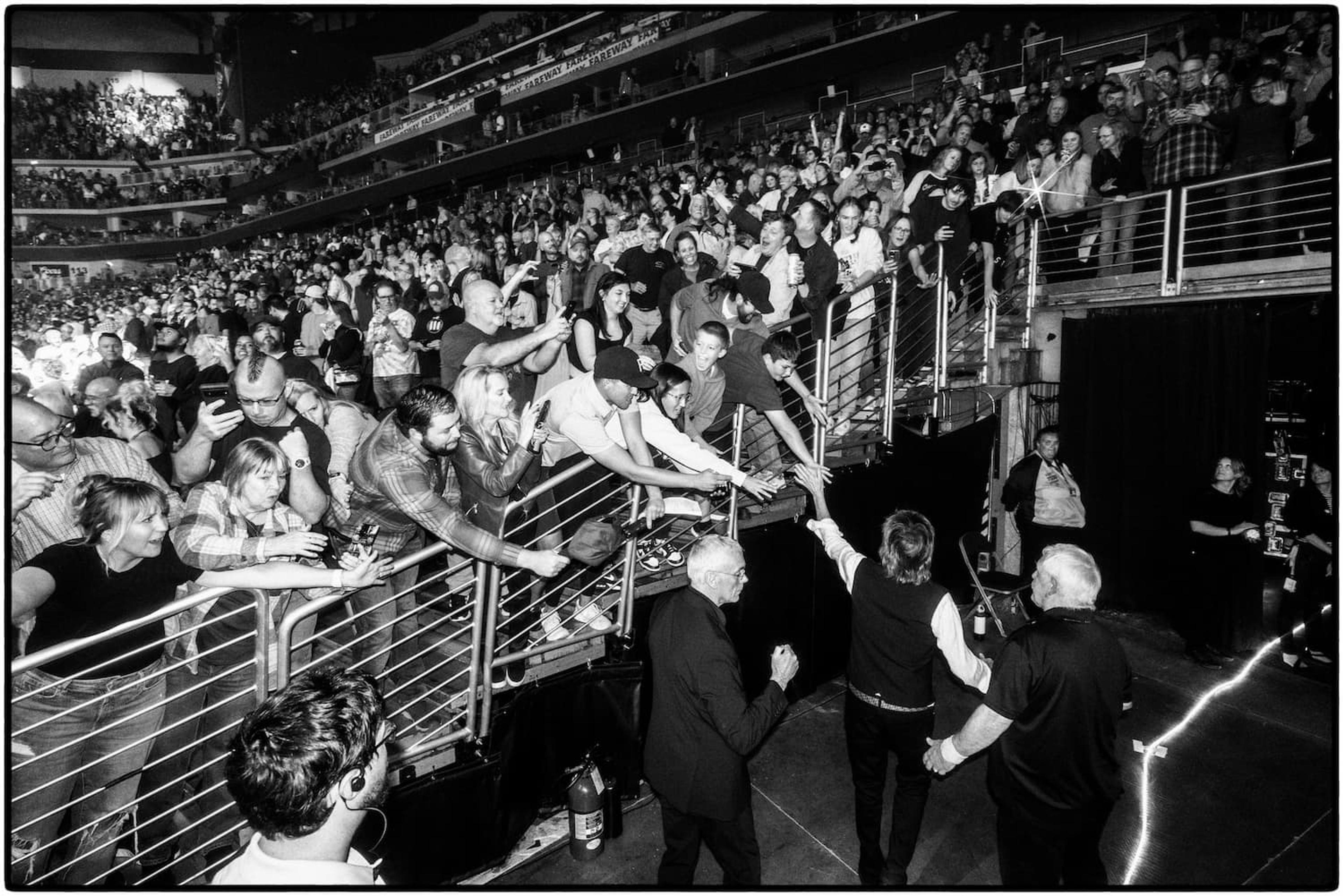 Black and white photo of Paul leaving the stage and high-fiving fans at Wells Fargo Arena in Des Moines, 2025. Photo by MJ Kim.
