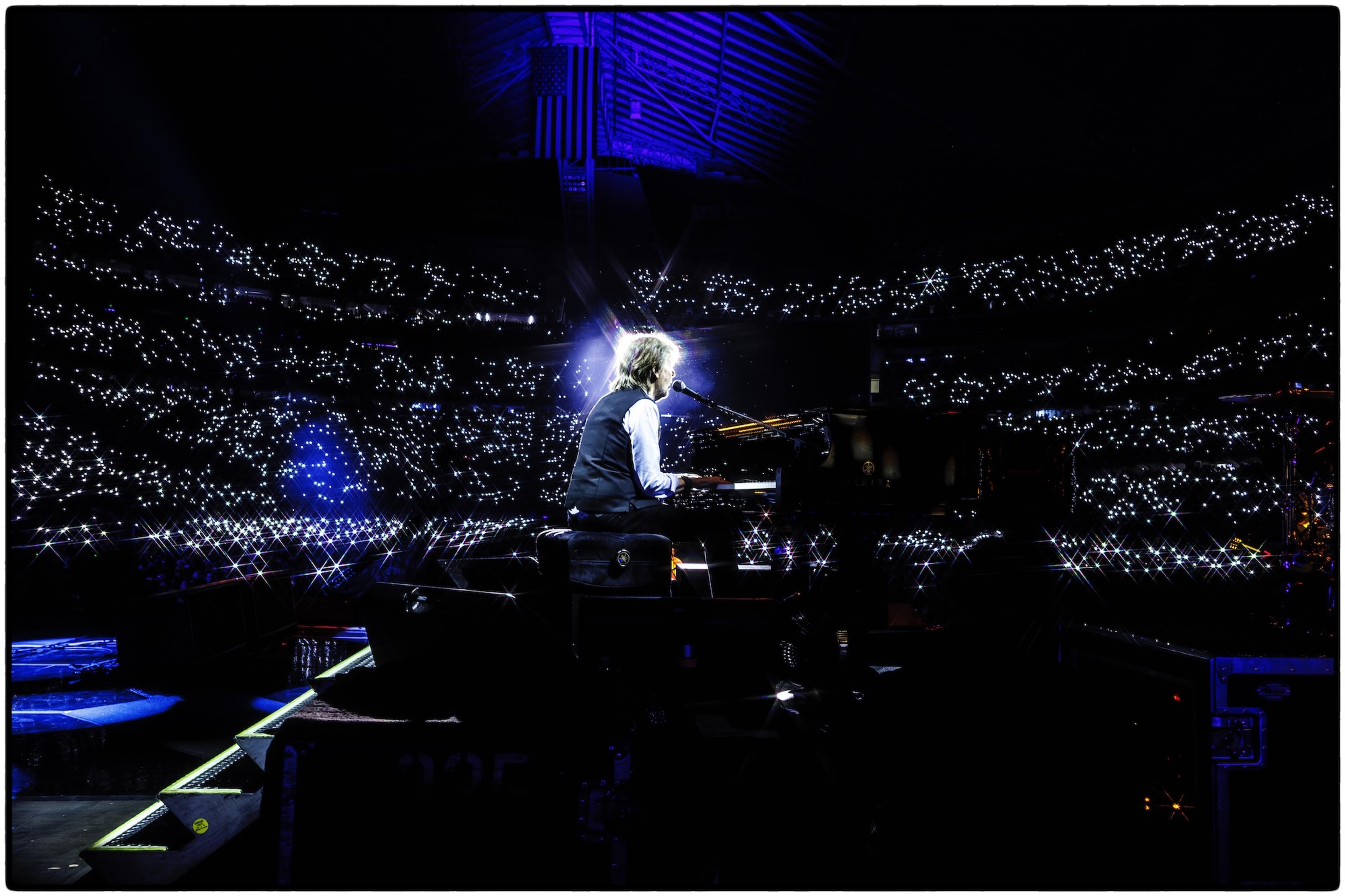 Colour photo of Paul performing at the piano, with the crowd at U.S. Bank Stadium in Minneapolis behind him.