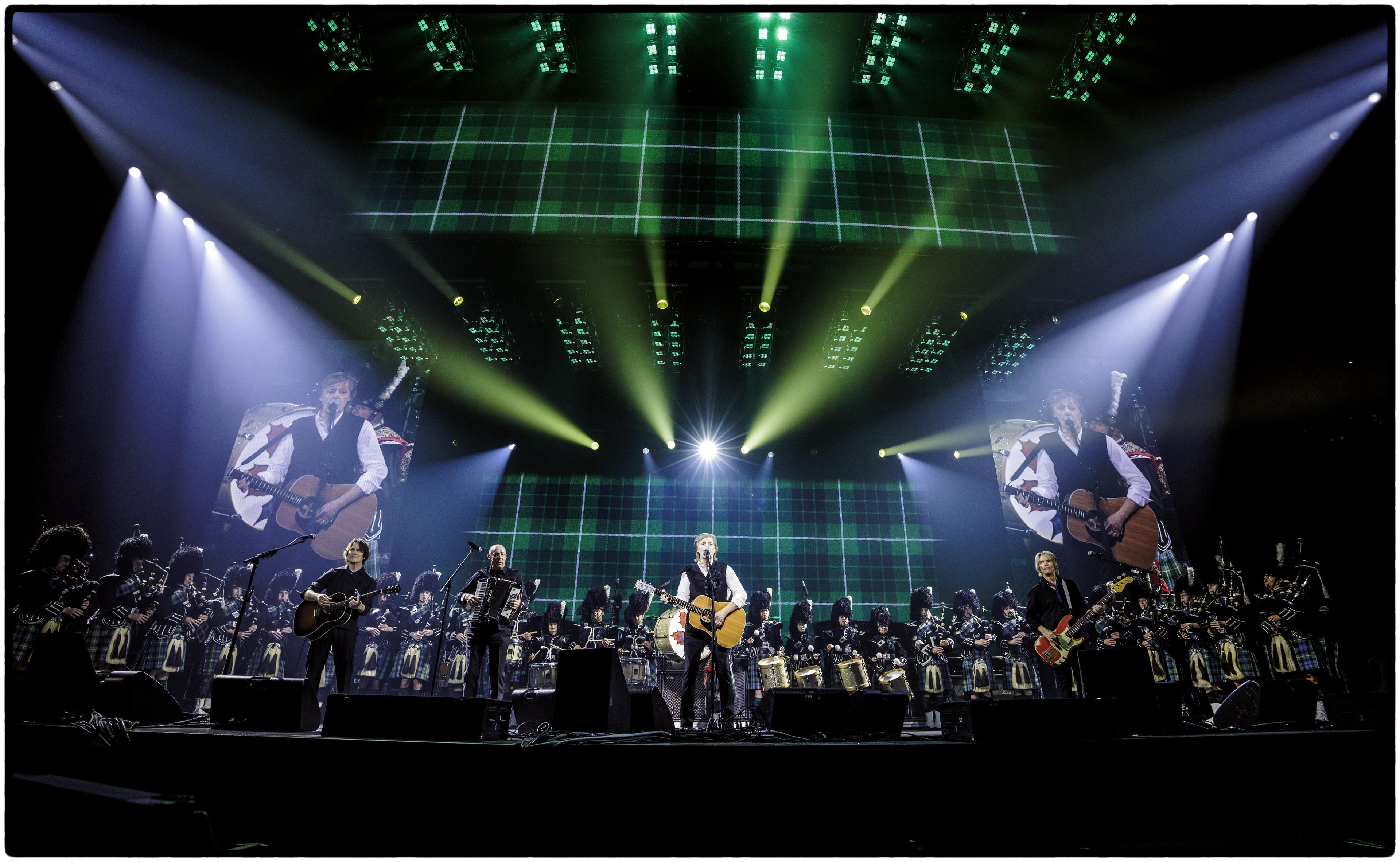 Paul McCartney on stage at Hamilton’s First Ontario Centre, flanked by the Paris Port Dover Pipe Band, with tartan-patterned tour screens in the background as he performs Wings’ classic 'Mull of Kintyre' during his 2025 GOT BACK tour.
