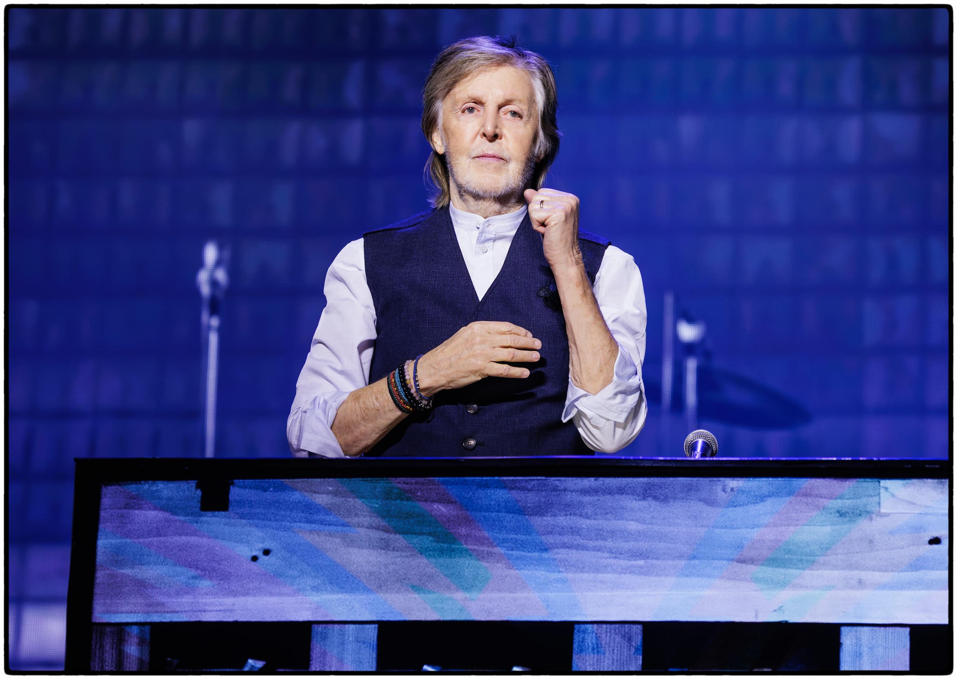 Portrait photograph of Paul McCartney surrounded by blue stage lights while standing at the Magic Piano at Buffalo’s KeyBank Center