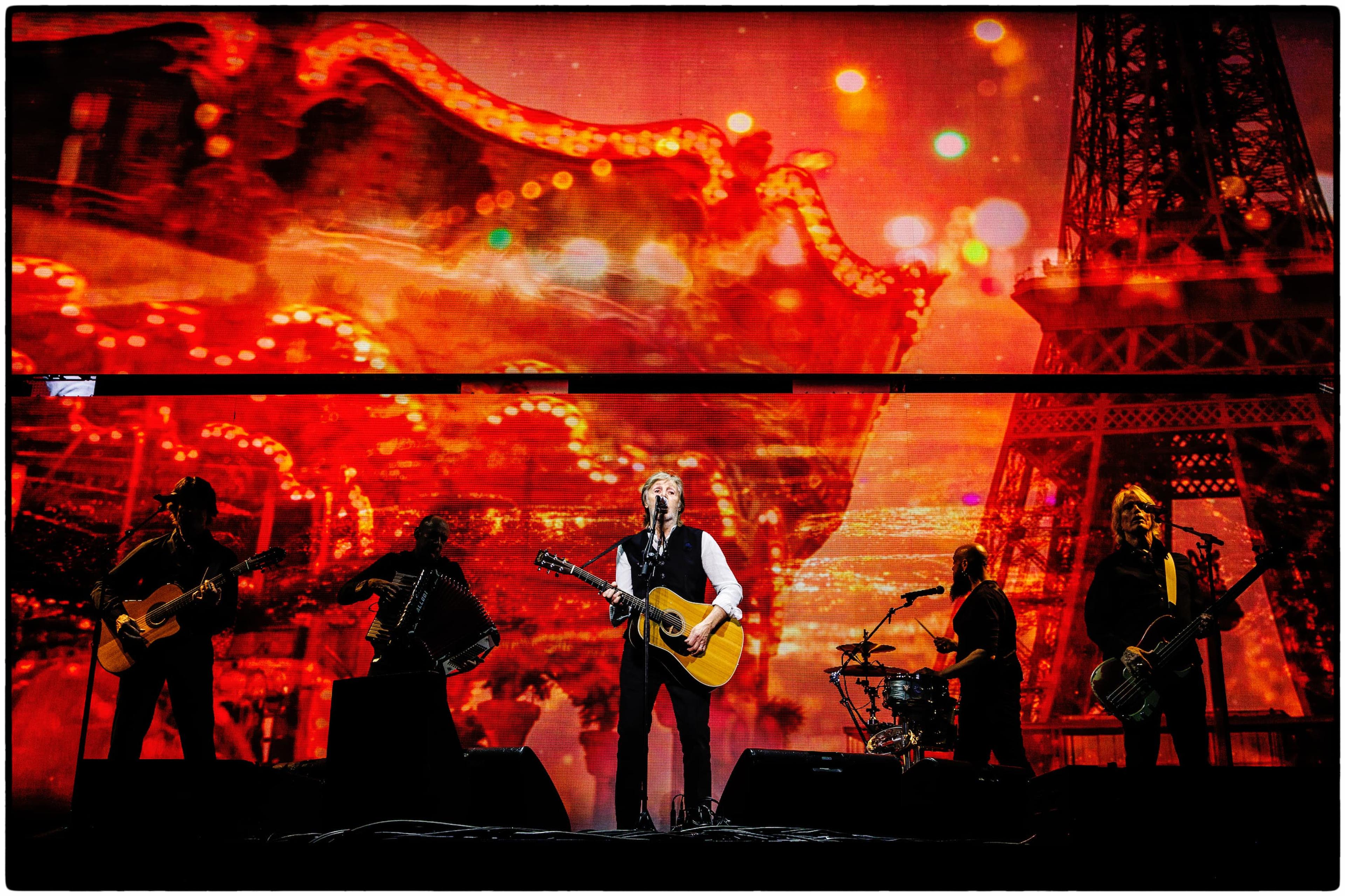 Paul McCartney on stage with his band at Montreal’s Bell Centre, with tour screens in the background displaying visuals for The Beatles’ classic “Michelle” during his 2025 “Got Back” tour.