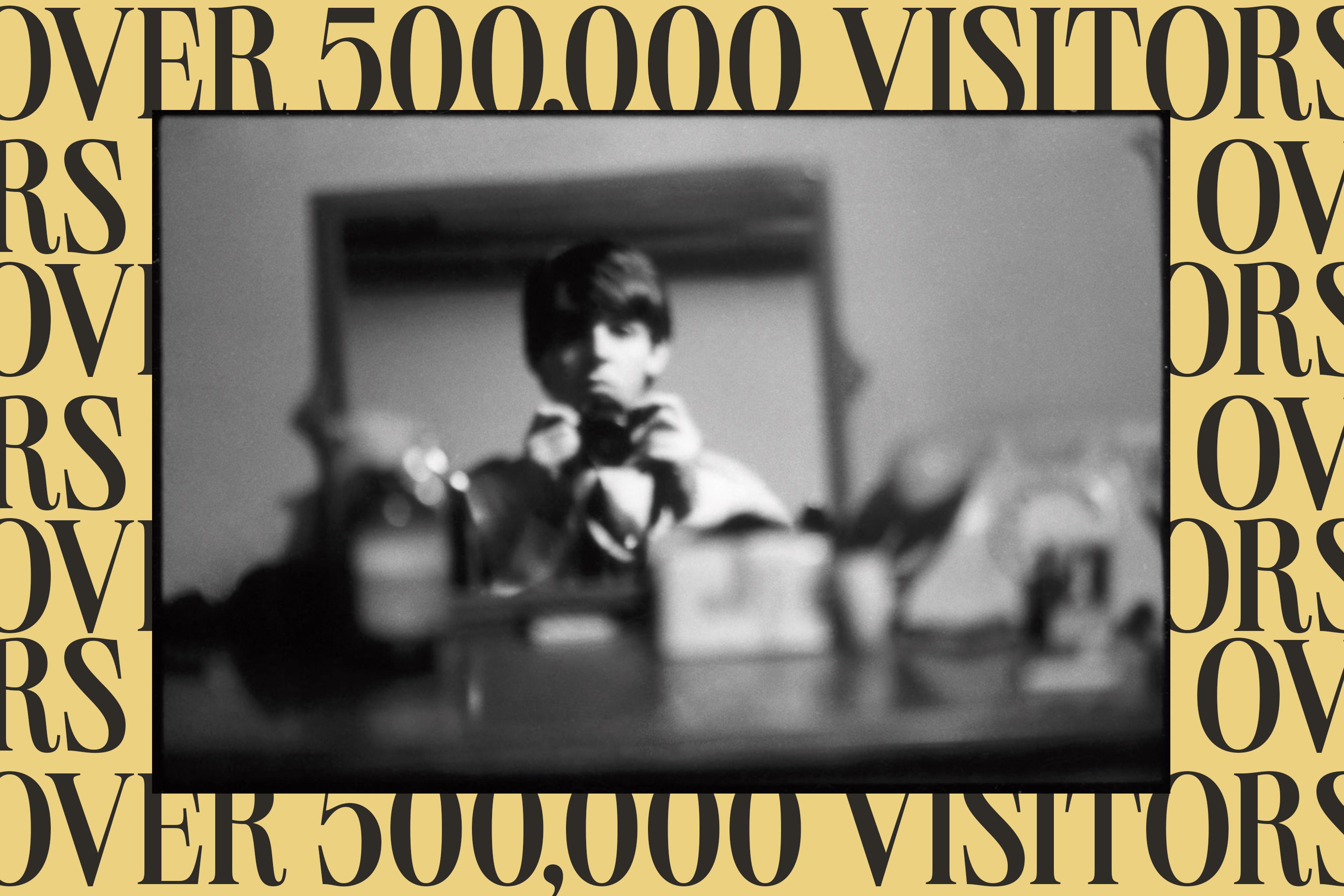 A stylized graphic featuring a self‑portrait of Paul McCartney, created to promote the exhibition “Paul McCartney Photographs 1963–64: Eyes of the Storm.” Beside the portrait, bold graphic text reads: “Over 500,000 visitors"