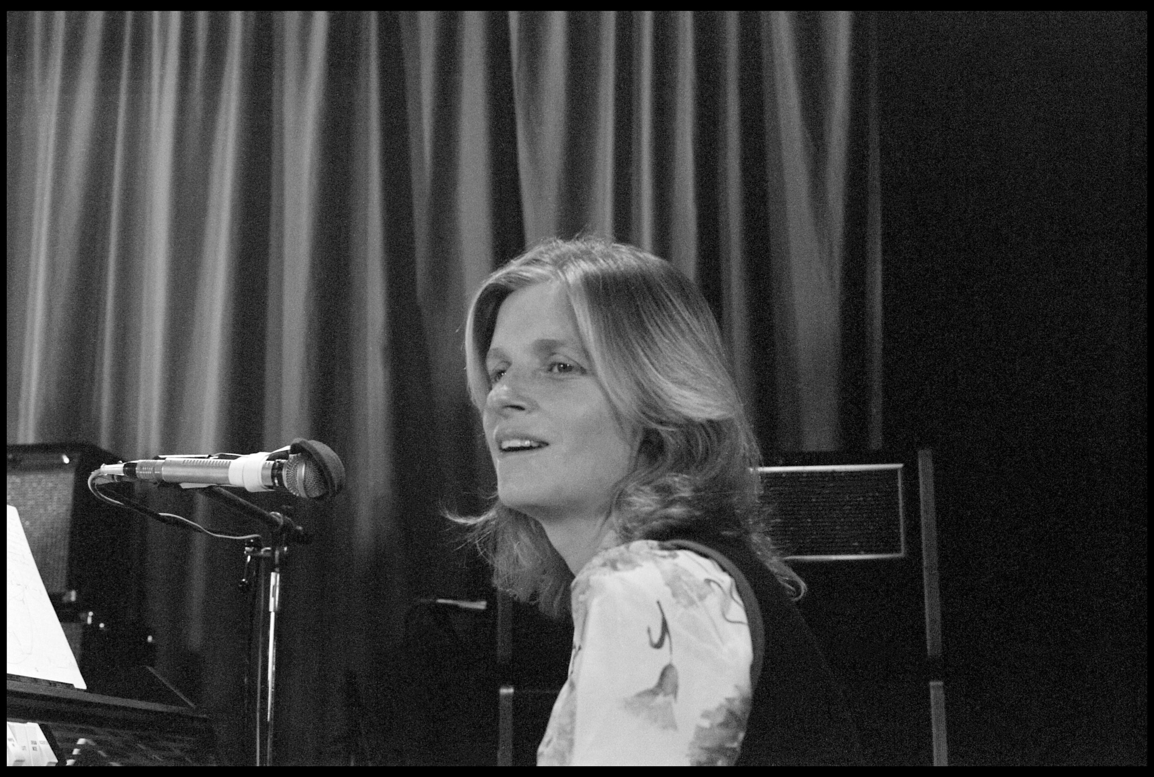 Black and white photograph of Linda McCartney at a microphone