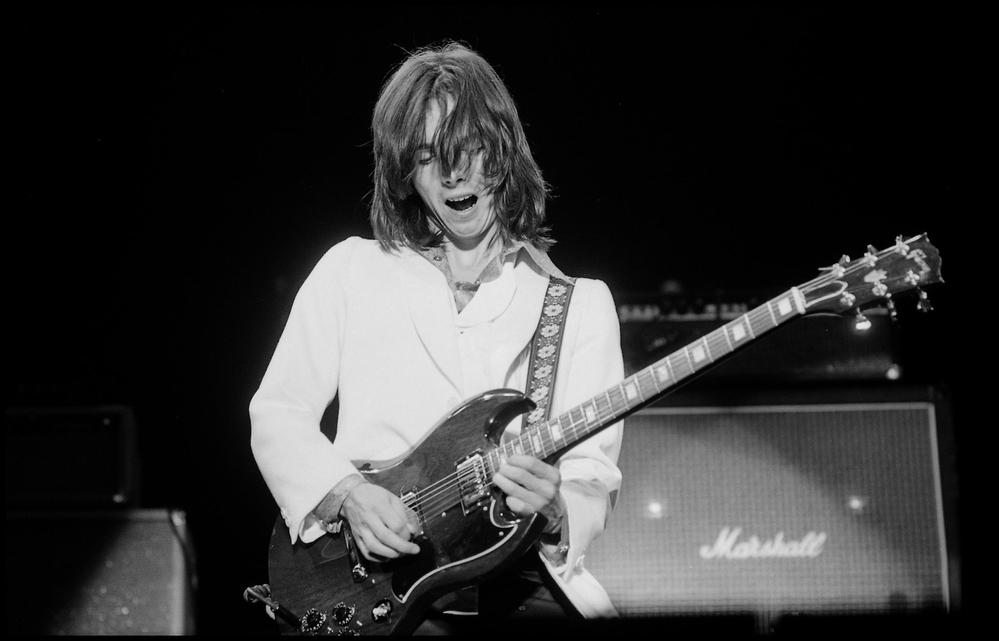 Black and white photograph of Jimmy McCulloch playing on stage