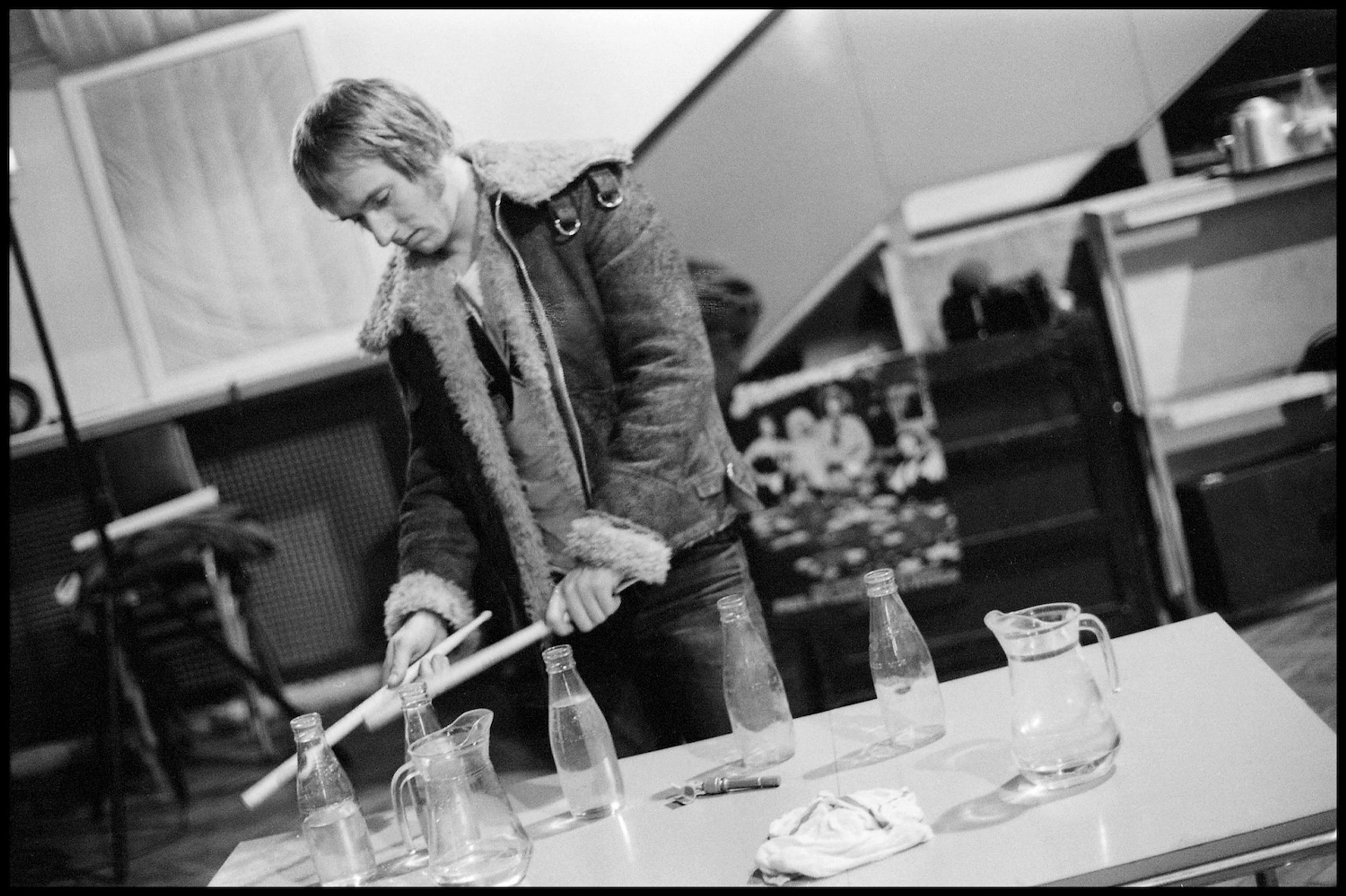 Black and white photograph of Geoff Britton playing the milk bottles in Abbey Road Studios