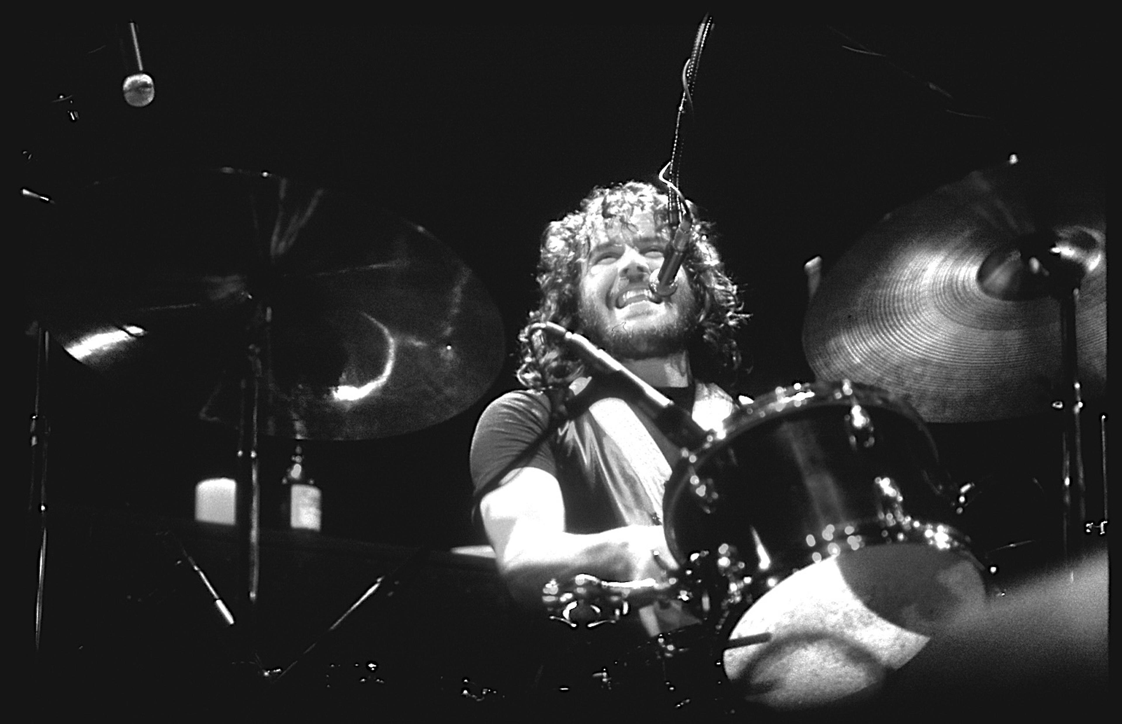Black and white photograph of Joe English playing the drums on stage