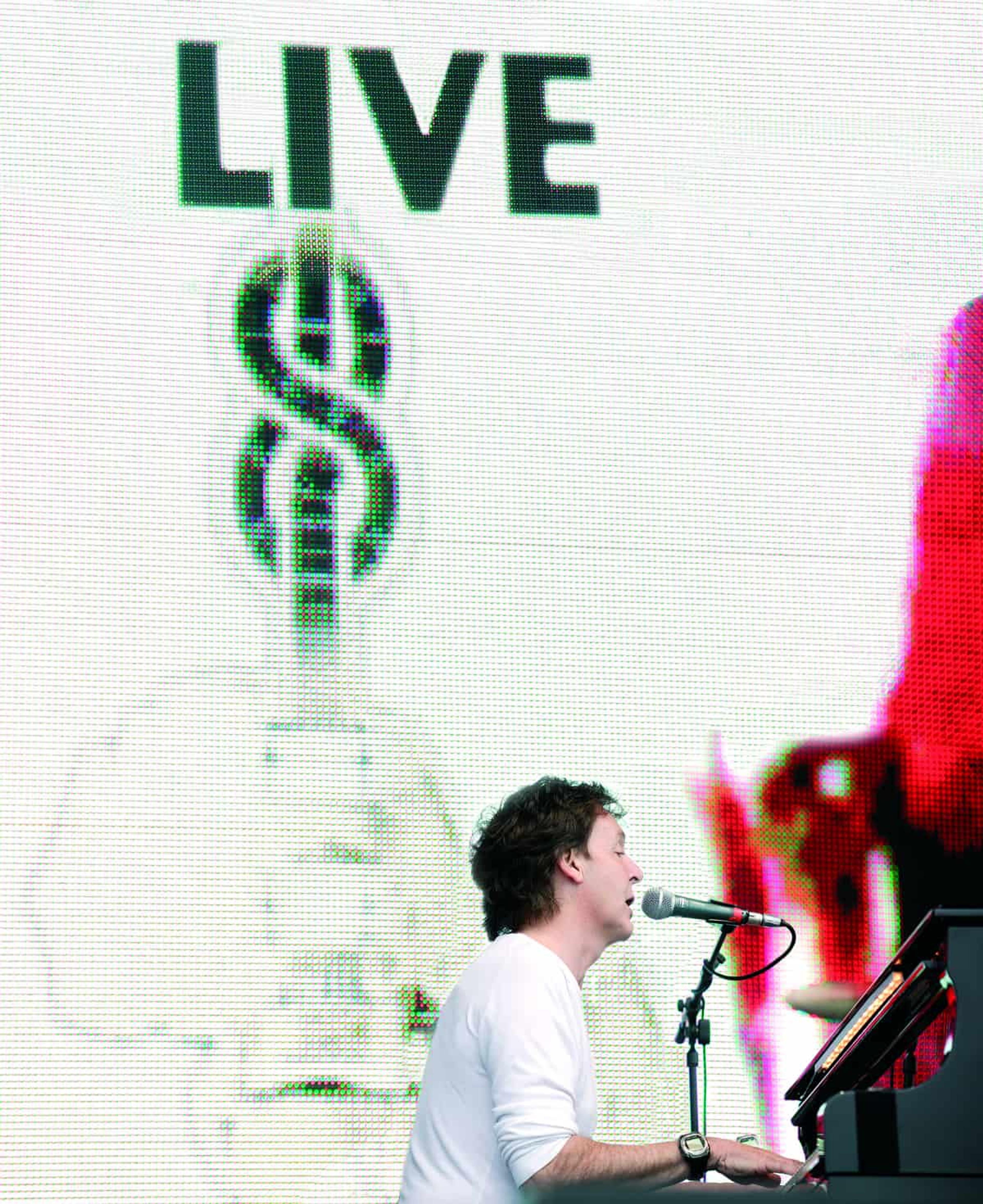 Paul sat at a piano in front of the Live 8 banner