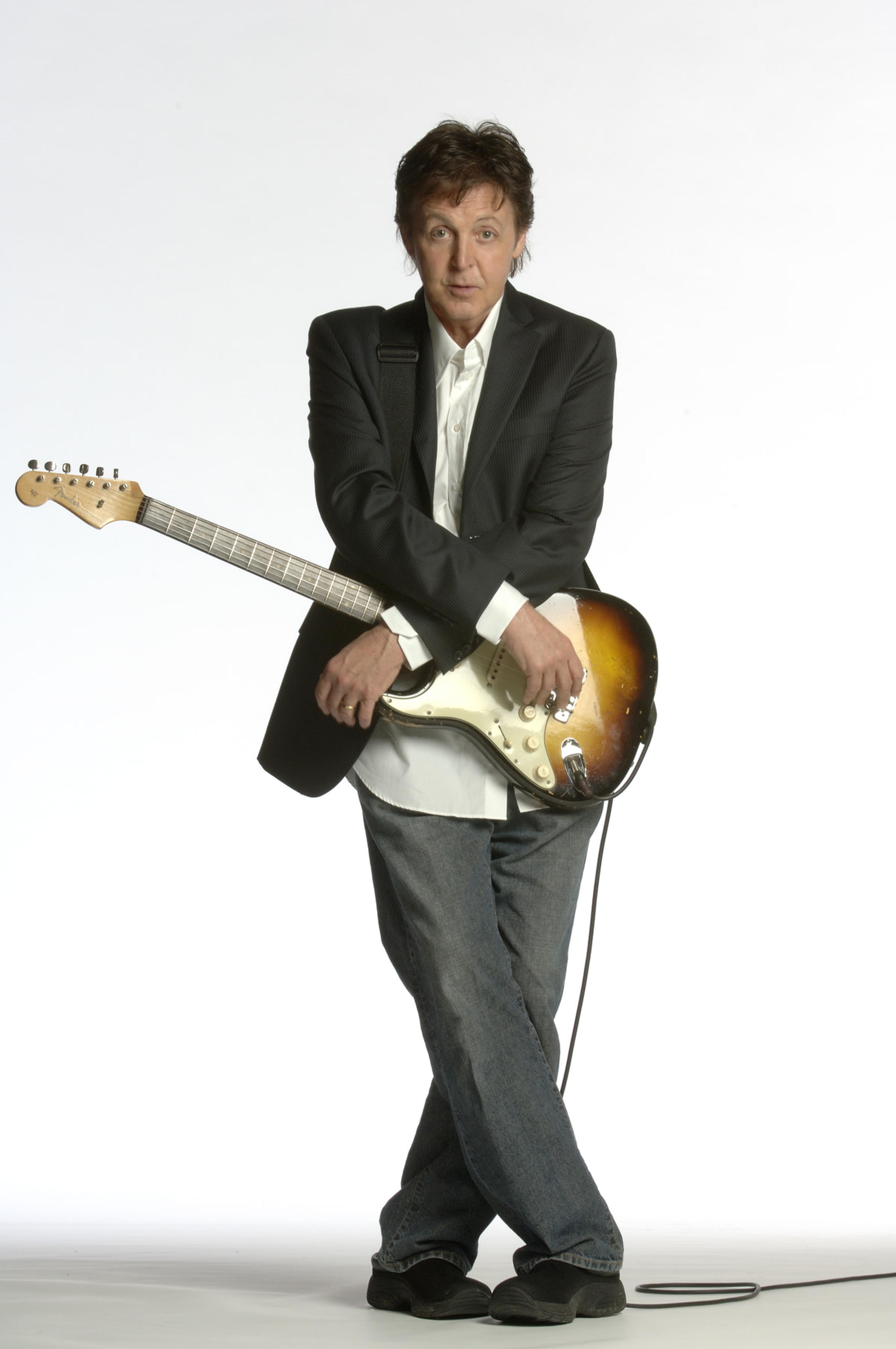 Paul standing with his arms crossed over an electric guitar