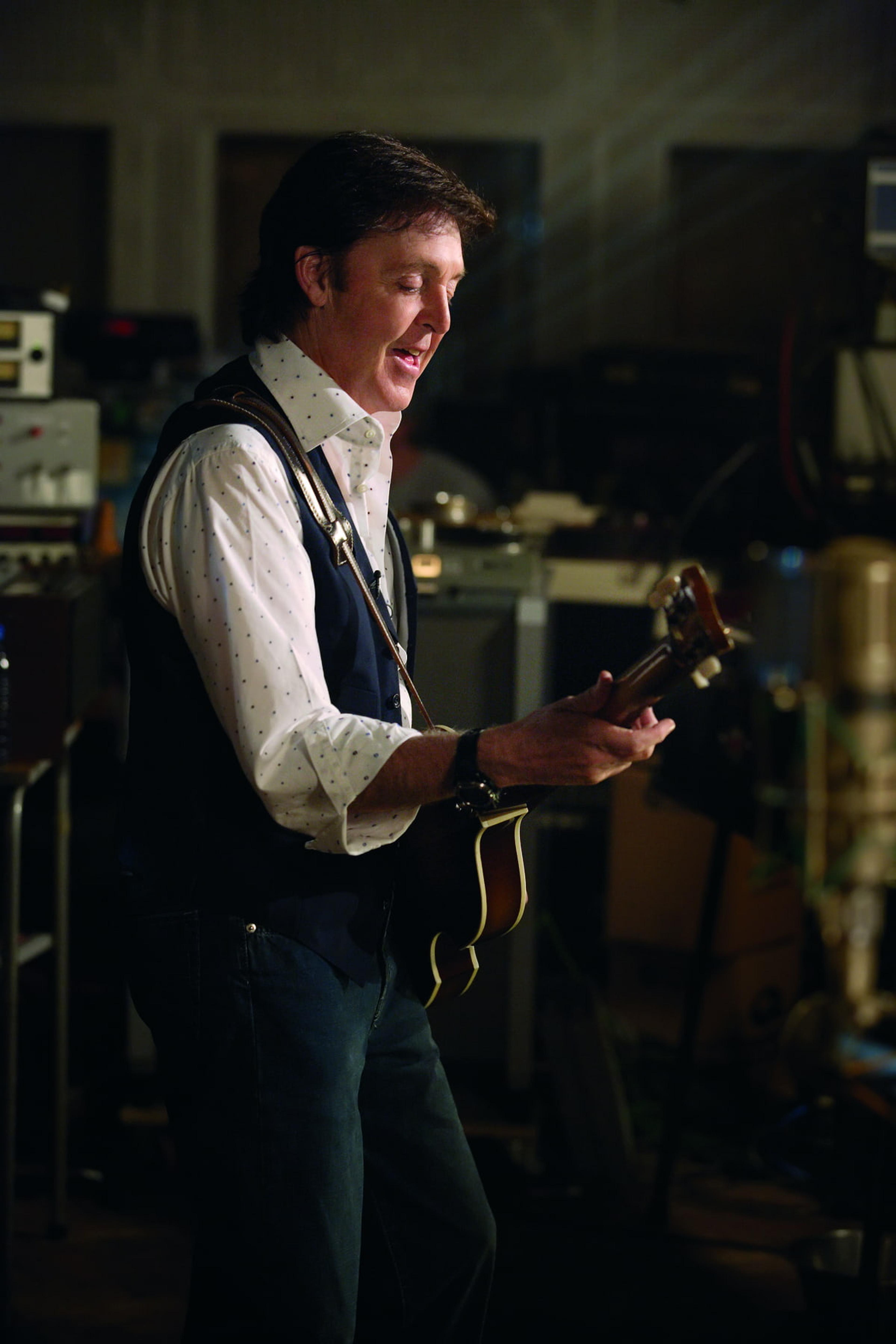 Paul smiling and playing guitar