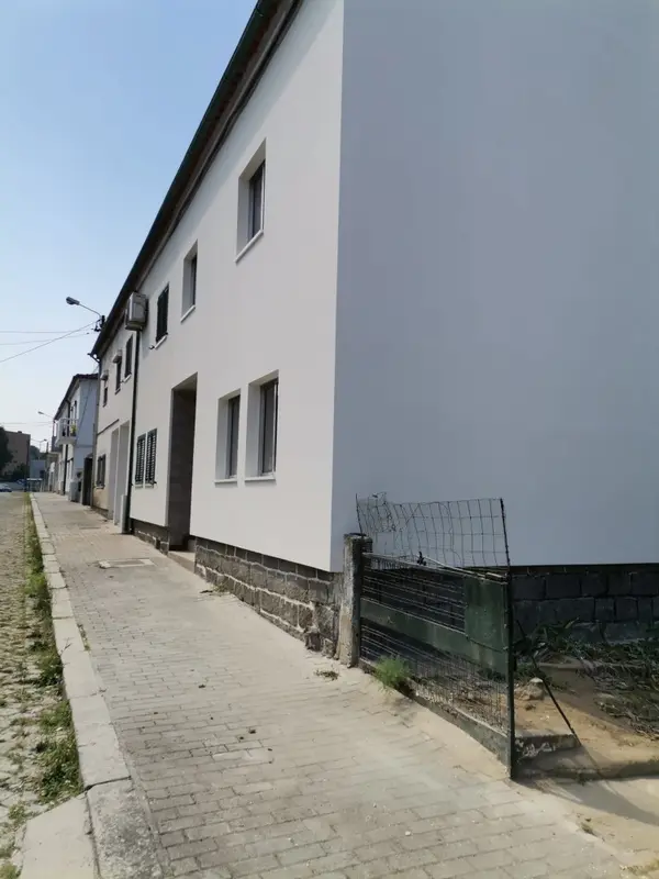 canto de fachada de uma casa de cor branca com uma porta e algumas janelas