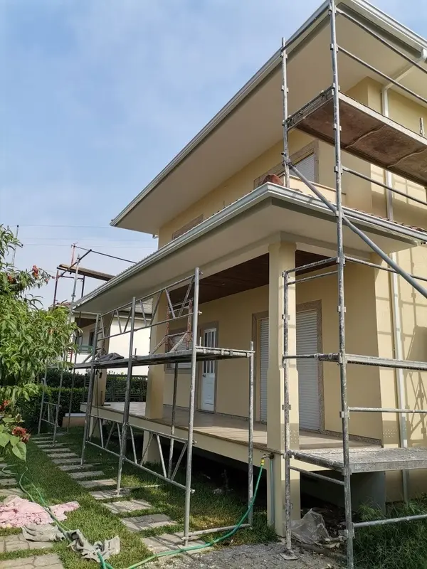 fachada de casa amarela com dois andares e andaimes em volta