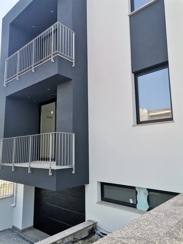 fachada de casa com arquitectura moderna em tons de preto e branco com duas varandas e uma garagem