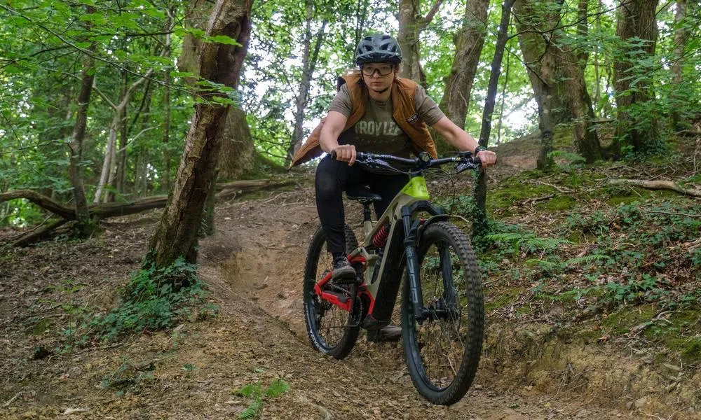 Woman riding an electric mountain bike in the woods wearing Troy Lee kit