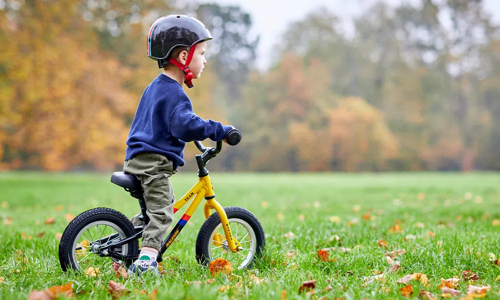 Child riding a balance bike on a grass field