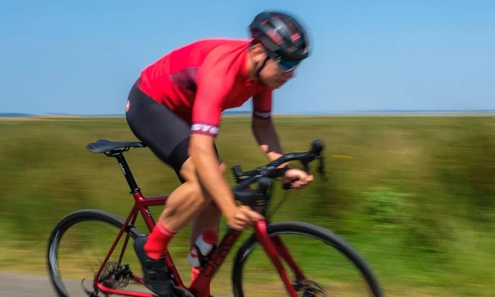 road cyclist riding fast in summer race kit