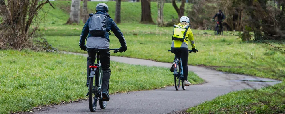 two cyclists riding through the park on an autumn day