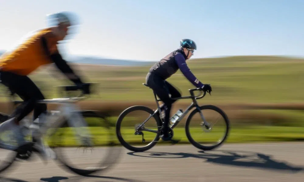 pan shot of two road cyclists riding across moorland in the Welsh hills