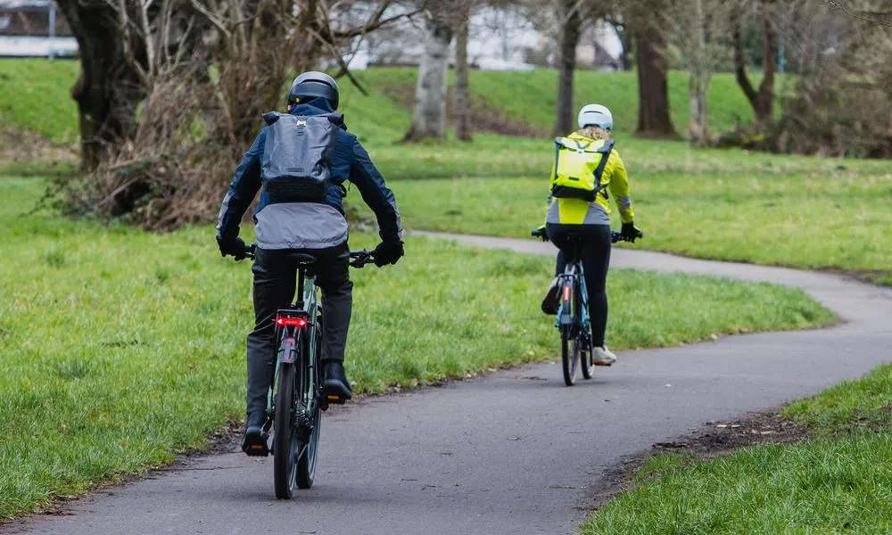 two cyclists riding along a winding cycle path in a park