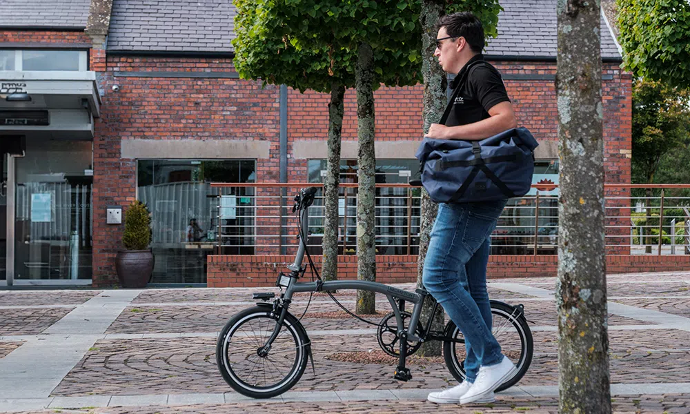 a folding Brompton bike is pushed past a cafe