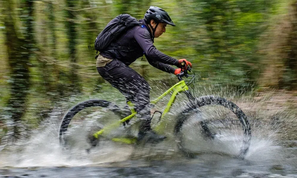 riding a Cannondale Scalpel mountain bike through a river with a front mudguard