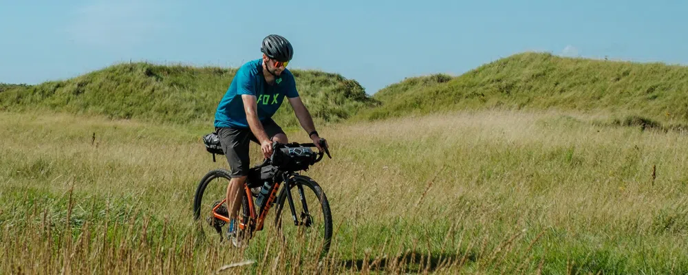 cyclist riding with frame and handlebar bags for bike packing