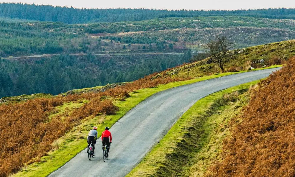 two road cyclists riding in the Welsh hills on a winter day