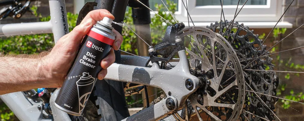 Spraying disc brake cleaner onto mountain bike disc brakes