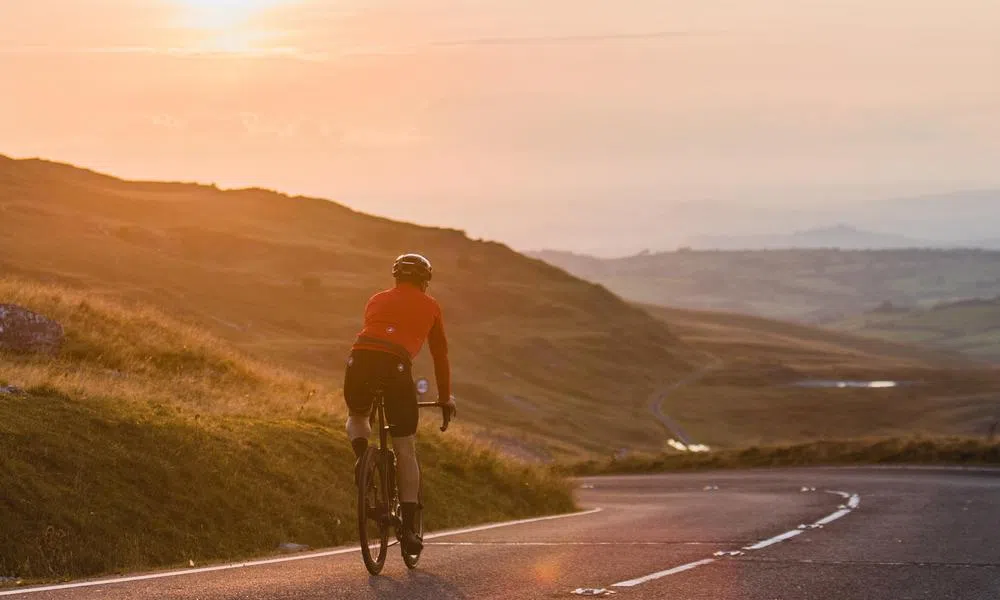 Cyclist descending road at sunset in the Welsh hills