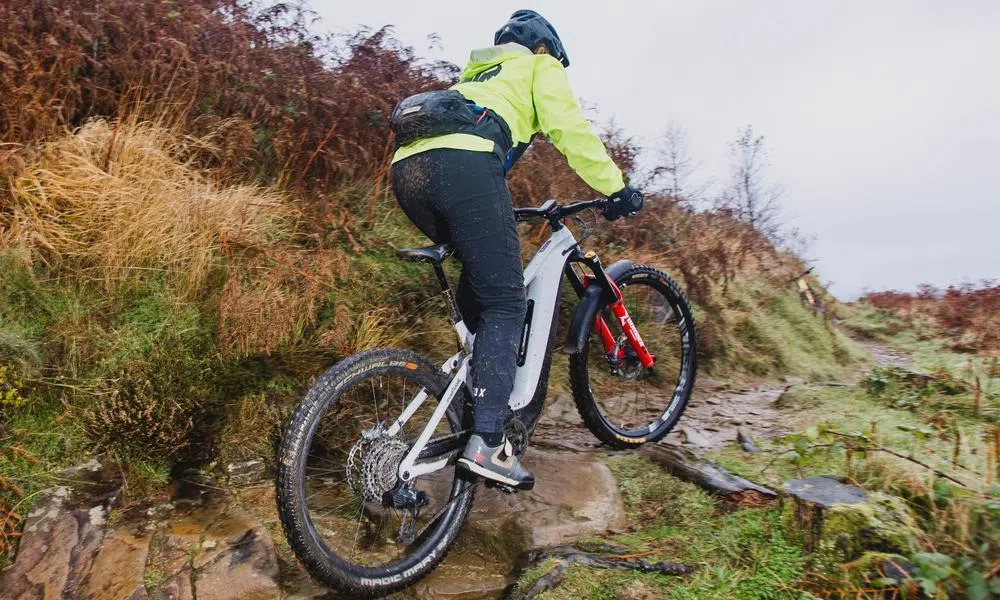 woman riding up an mtb trail on an e-bike on a misty day