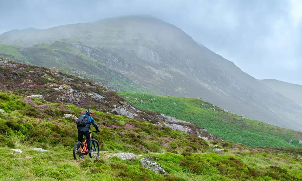 mountain biker riding past a Welsh hill on a wet summer day