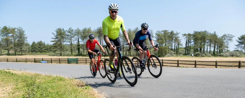 riders on power meter pedals climb a hill