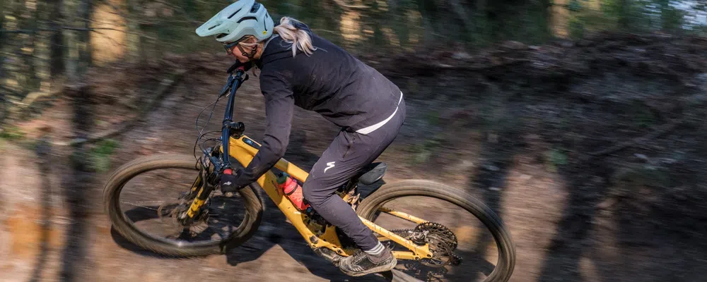 woman riding an electric mountain bike on traisl int the woods