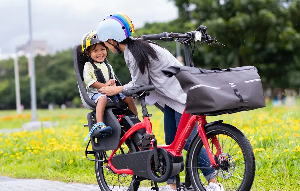 Woman tending to happy child sat on the back on a e-bike