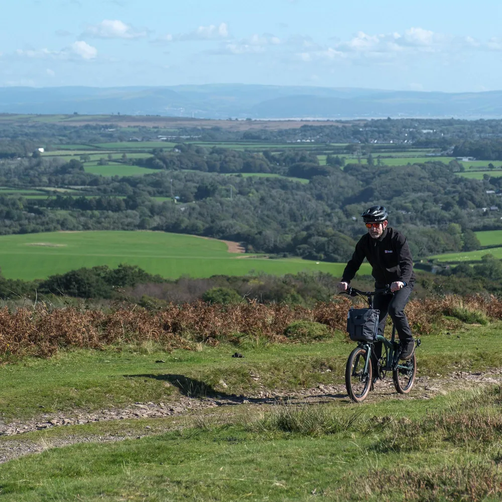 Riding a Brompton G Line Electric on a gravel track in the Welsh hills