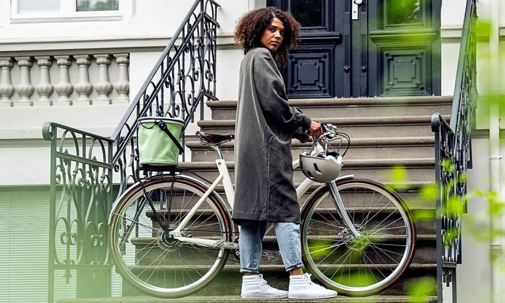 woman standing next to a bike with a trunk bag attached to rear rack