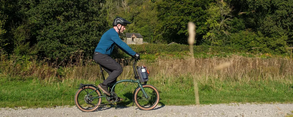 riding a Brompton g line electric bike on a gravel track 