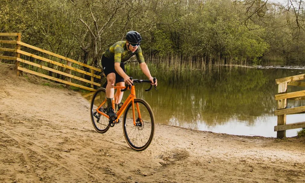 a gravel bike is ridden past a lake