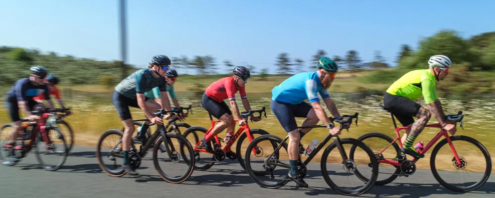 road cyclists riding past in a group on a sunny day