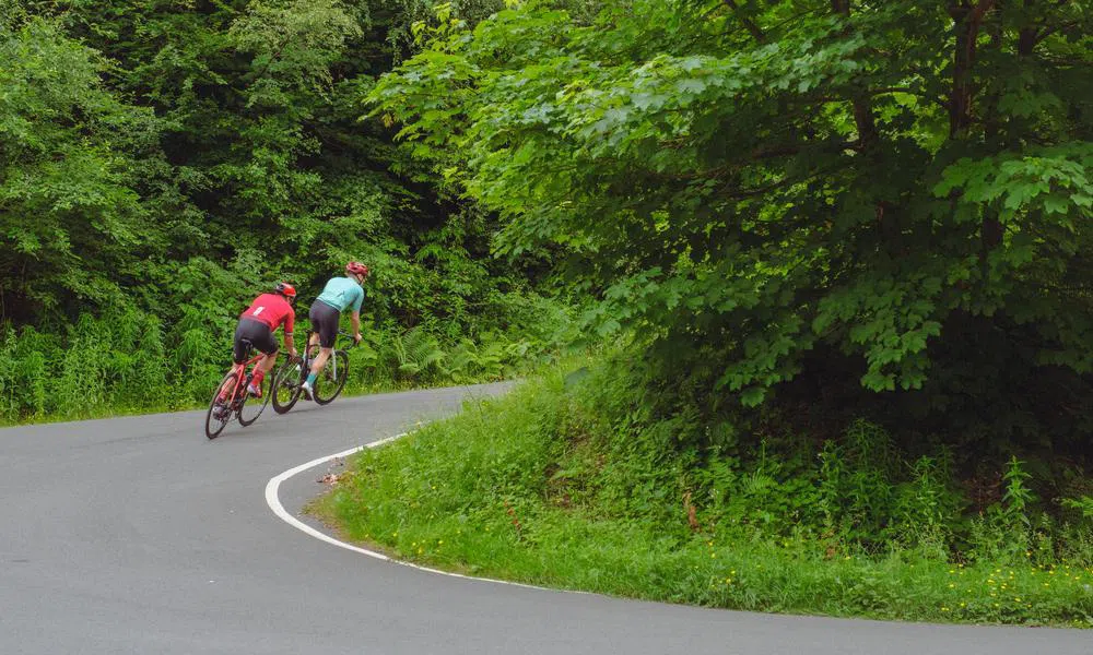 two cyclists on road climb corner