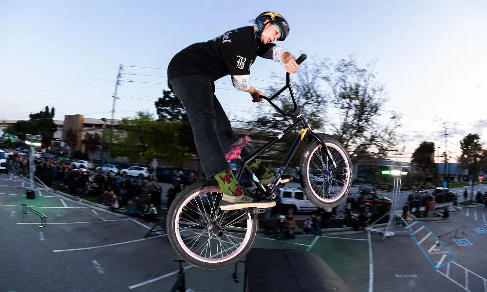 a bmx rider jumps through the air doing an x-up