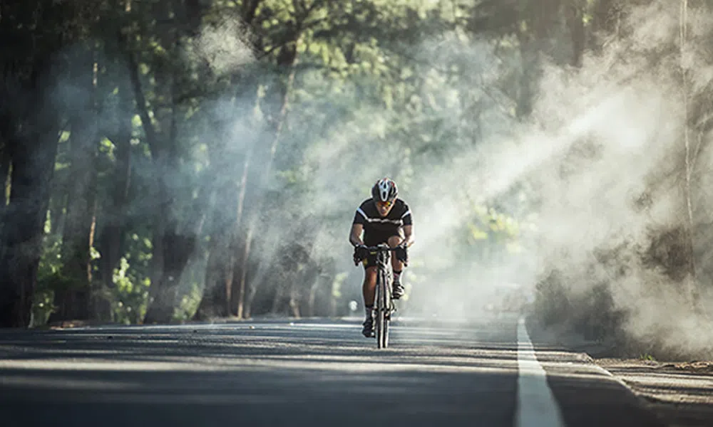 cyclist cycling through sun rays 