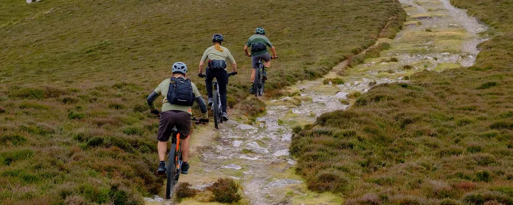 three mountain bikers riding a rough open track in Wales