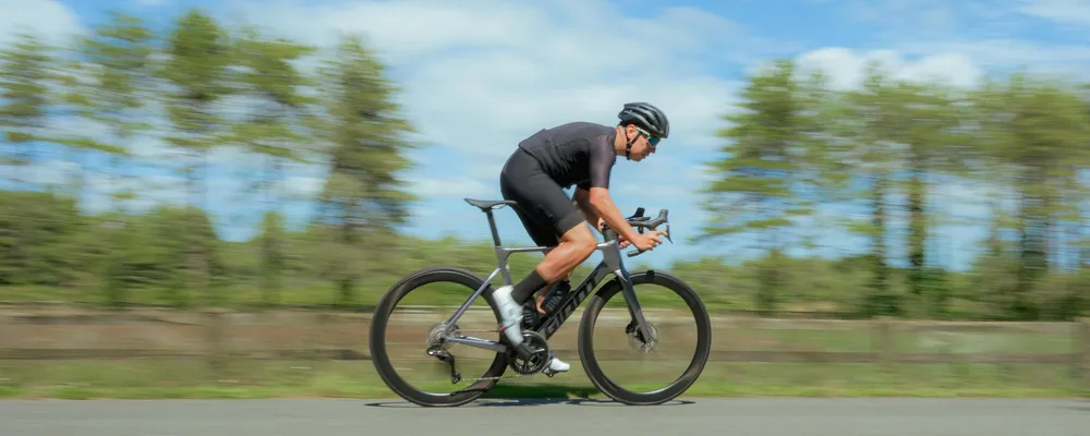 riding a Giant tcr road bike in black riding kit on a summer day
