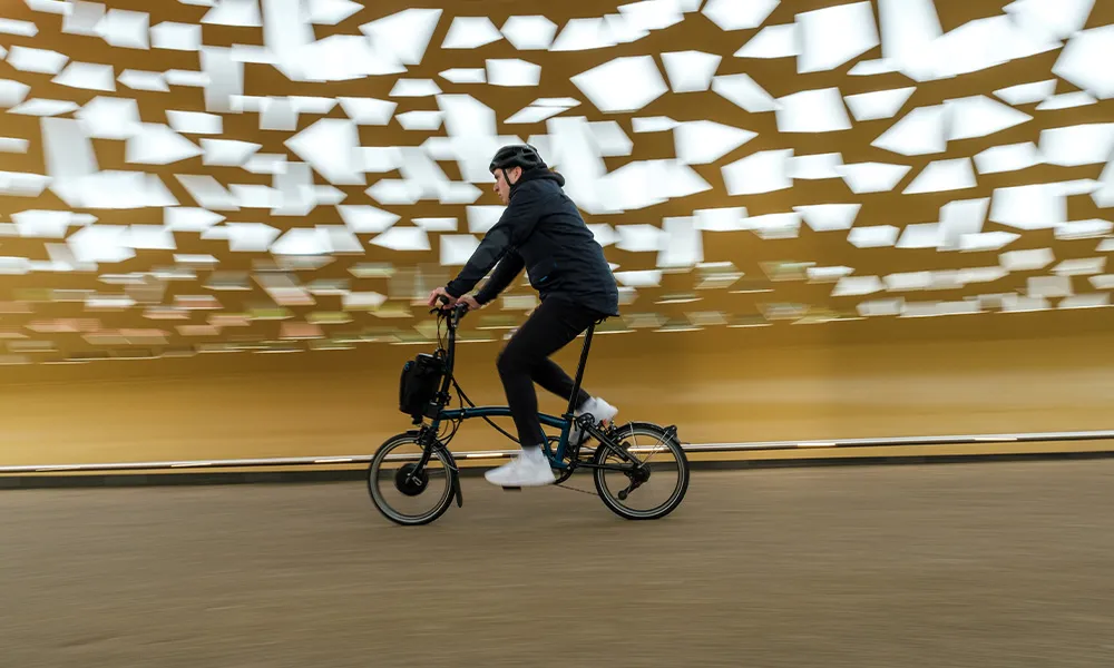 Commuter crossing a bridge on a brompton