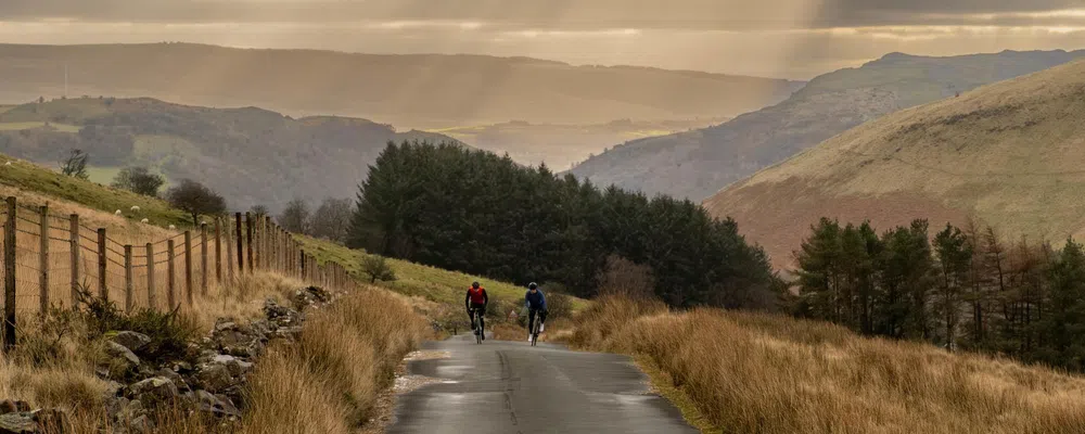 two road cyclists climbing in the Welsh hills on a moody winter day