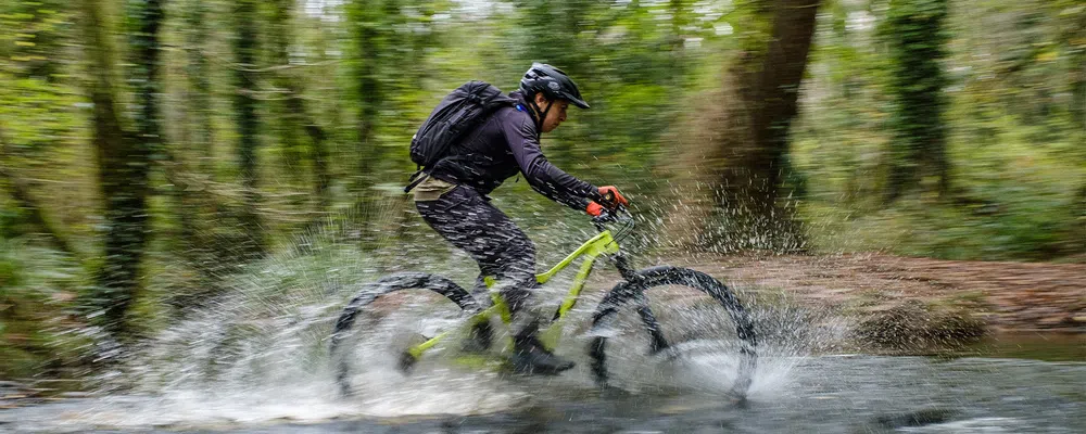 a mountain bike with a bright frame is ridden through a stream