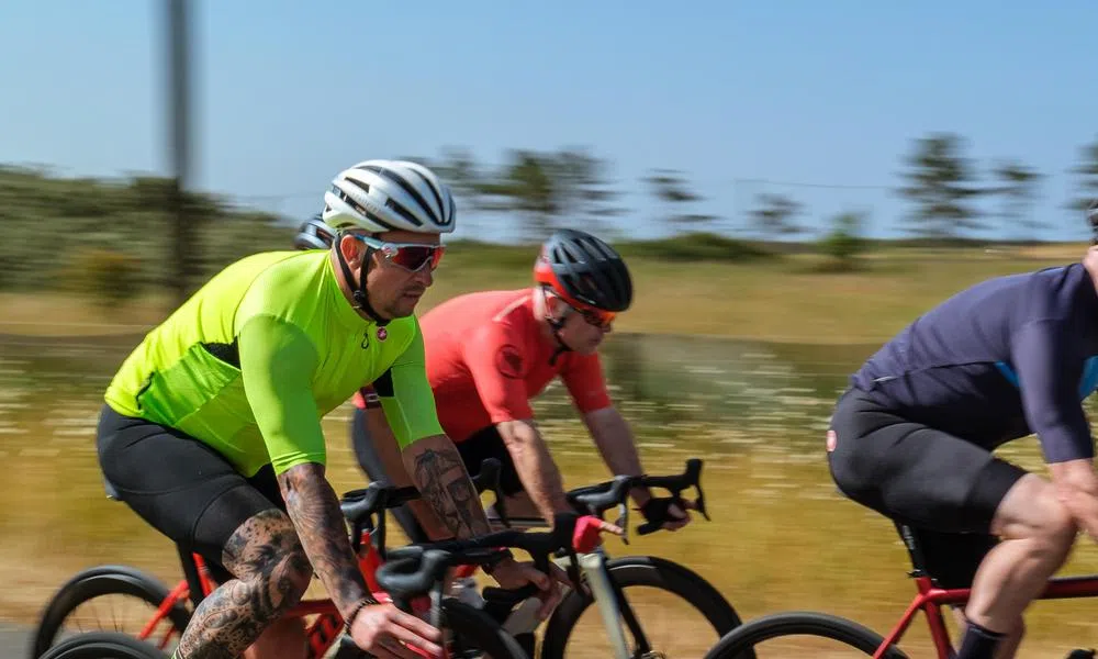 two road cyclists close up on a summer day pan shot