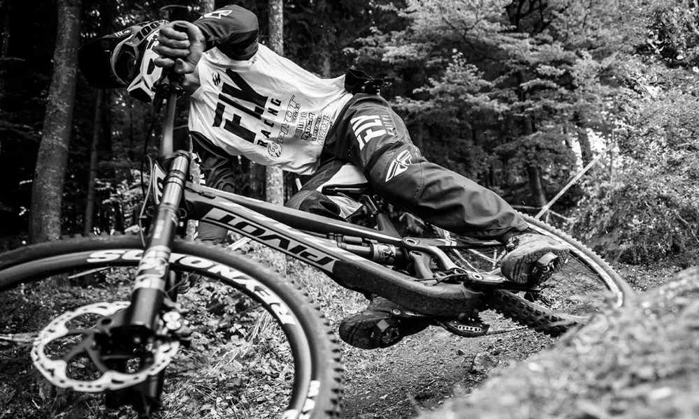 Downhill mountain bike racer on a Pivot Phoenix DH bike BW closeup 