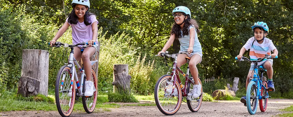 3 kids riding bikes of different sizes in the park