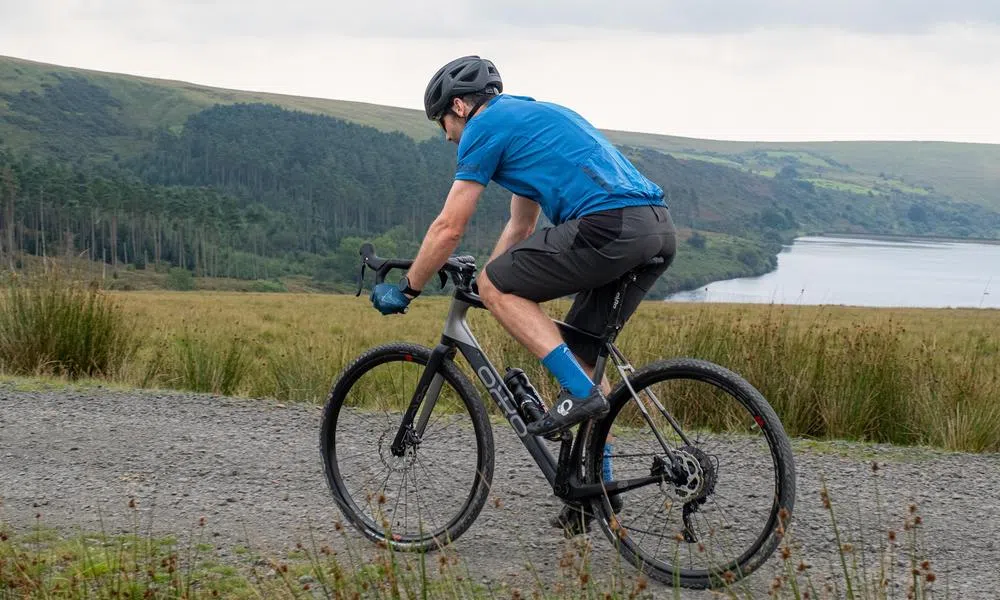 cyclist riding along a gravel track above a lake